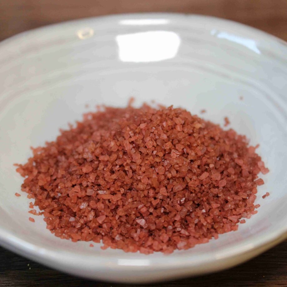 Sel rouge d'Hawaï dans un bol blanc sur une table en bois, prêt à sublimer vos plats avec une touche exotique.