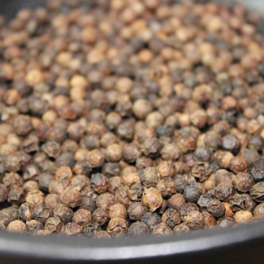 Grains de poivre noir dans un bol, essentiels pour assaisonnement et saveur en cuisine.