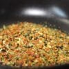 Mélange coloré d'épices et d'herbes dans un bol noir, idéal pour assaisonner vos plats et enrichir leurs saveurs.