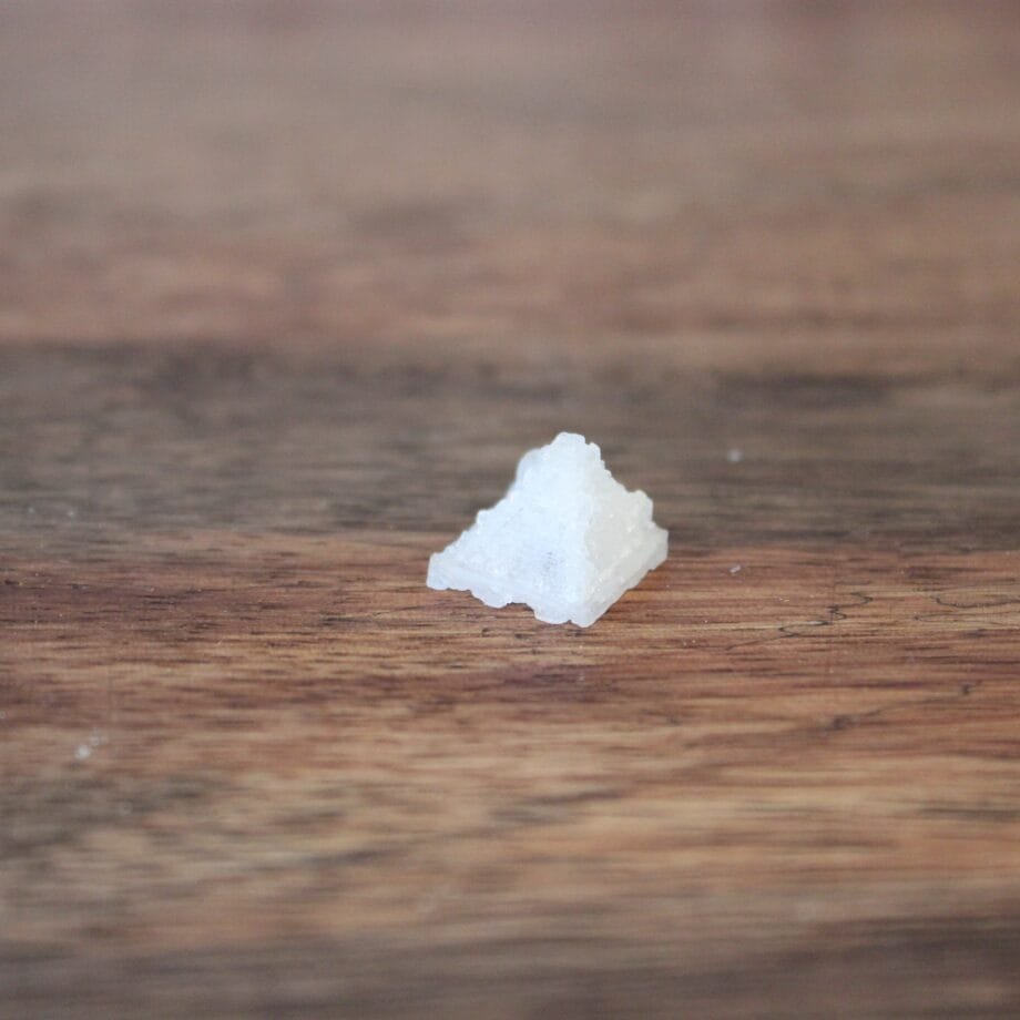 Cristal de sel en forme de pyramide sur une table en bois.