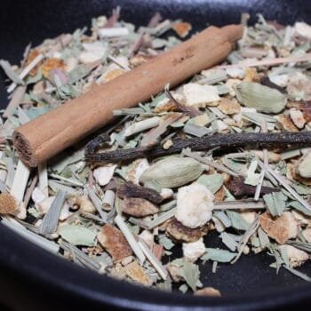 Un mélange de thé chai comprenant cannelle, citronnelle, cardamome et autres épices dans un bol noir.