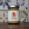 Bocal de sauce piquante Haban's flambée posé sur une table en bois avec motif de fond géométrique.