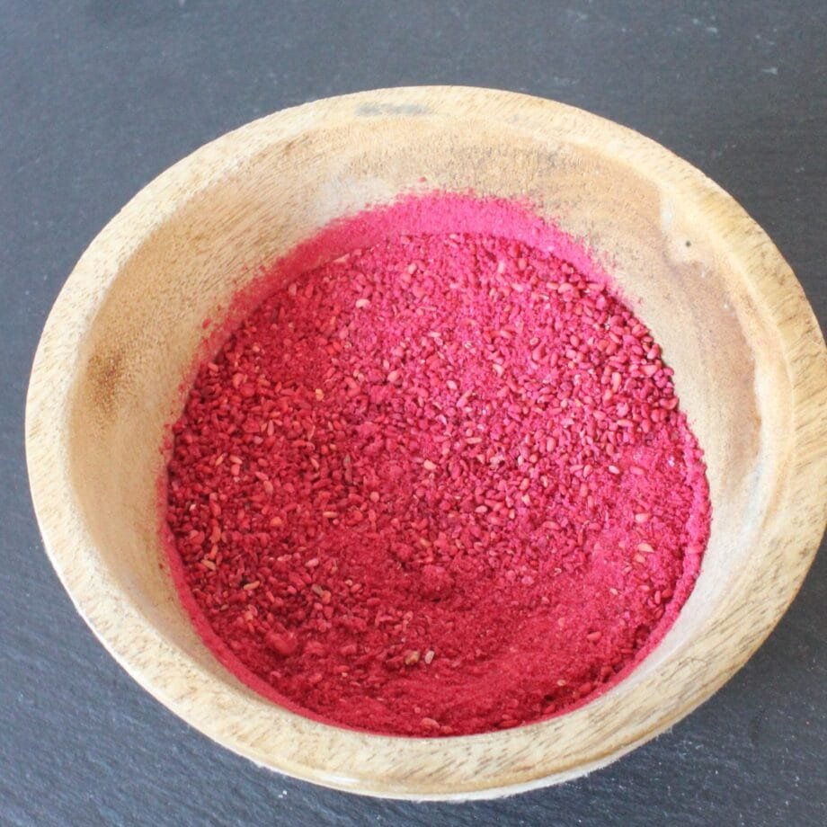 Poudre de betterave rouge dans un bol en bois sur fond sombre, utilisée pour la cuisine et la nutrition naturelle.