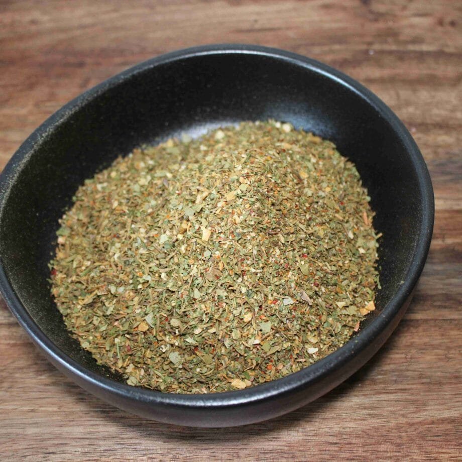 Bol de fines herbes séchées pour assaisonnement sur une table en bois. Parfait pour la cuisine méditerranéenne.