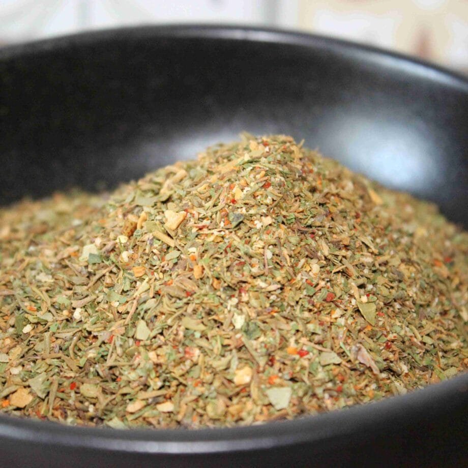 Mélange d'herbes séchées dans un bol noir, parfait pour relever les plats savoureux et ajouter une touche aromatique.