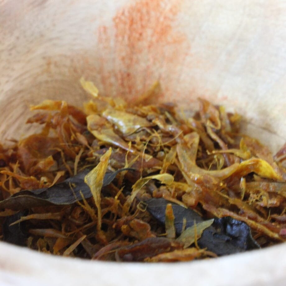 Mélange de feuilles séchées dans un bol en bois, ingrédients naturels pour infusion ou cuisine.
