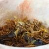 Mélange d'herbes séchées et d'épices dans un bol en bois, illustrant une préparation culinaire traditionnelle.