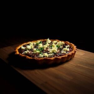 Tarte sucrée aux fruits et fromage râpé, posée sur une table en bois, éclairée par la lumière du jour.