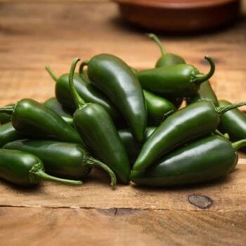 Piments jalapeños verts frais sur une table en bois, parfaits pour épicer vos recettes culinaires.