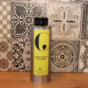 Bouteille d'huile d'olive et citron devant des carreaux décoratifs en noir et blanc.