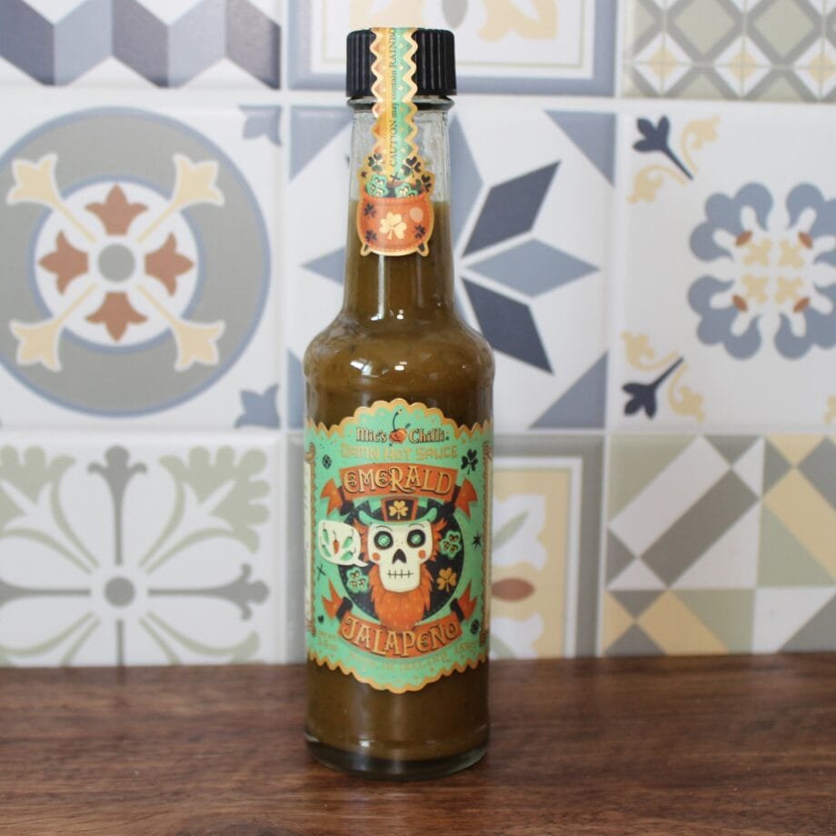 Bouteille de sauce piquante jalapeño Emerald, fond de carreaux colorés, design mexicain vibrant.