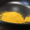 Poudre de curry jaune vif dans un bol noir, parfaite pour rehausser vos plats avec une saveur exotique et épicée.