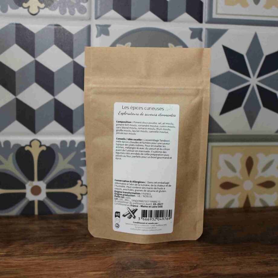 Sachet d'épices variées devant un mur de carreaux décoratifs, parfait pour rehausser vos plats avec des saveurs uniques.