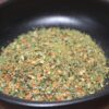Assaisonnement épicé dans un bol noir, mélange coloré d'herbes et épices séchées pour rehausser vos plats.