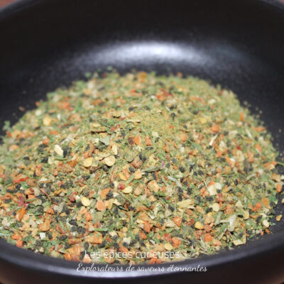 Assaisonnement épicé dans un bol noir, mélange coloré d'herbes et épices séchées pour rehausser vos plats.
