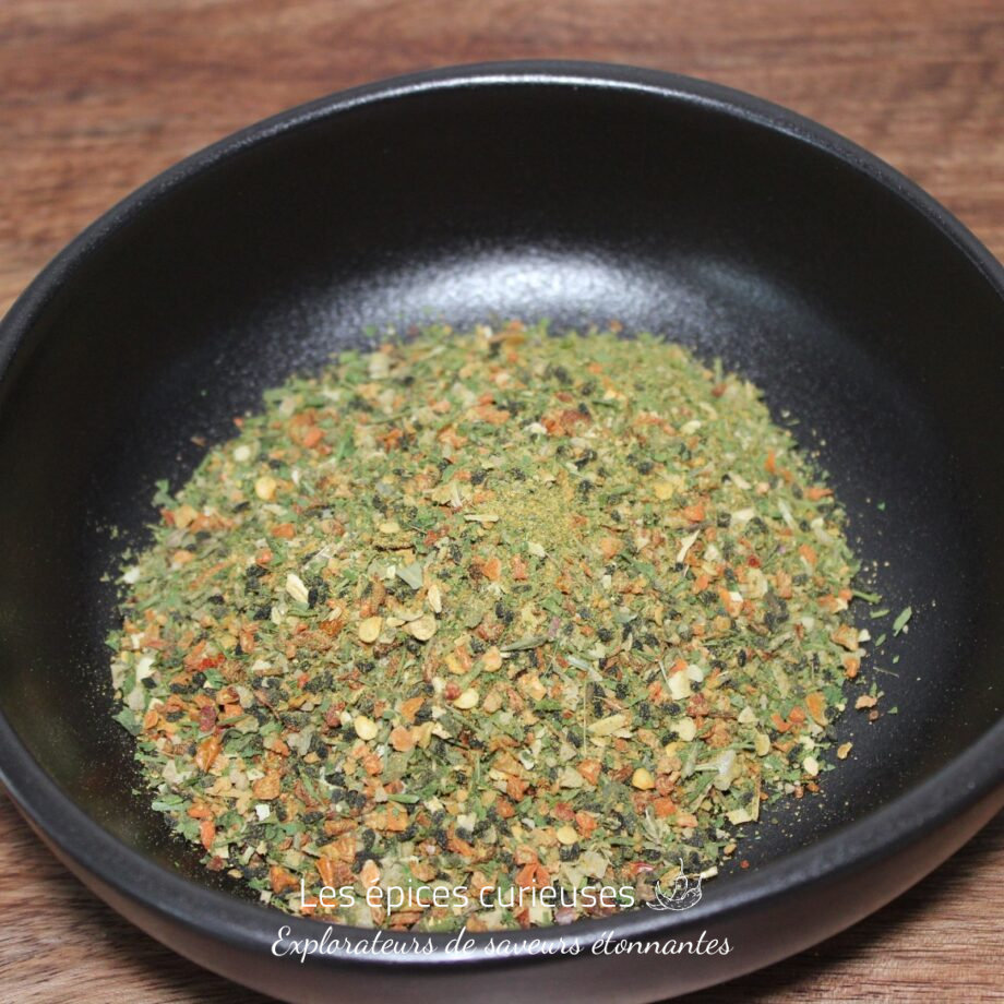 Mélange d'épices séchées dans un bol noir sur une table en bois, prêt pour la cuisine.