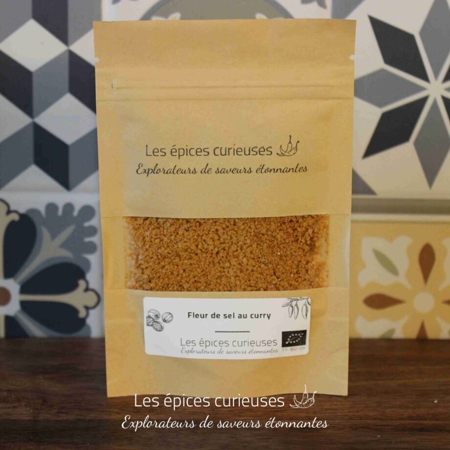 Sachet de fleur de sel au curry Les épices curieuses sur fond de carreaux décoratifs.