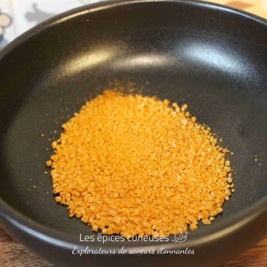 Granulés d'orange déshydratée dans un bol noir pour préparation culinaire.