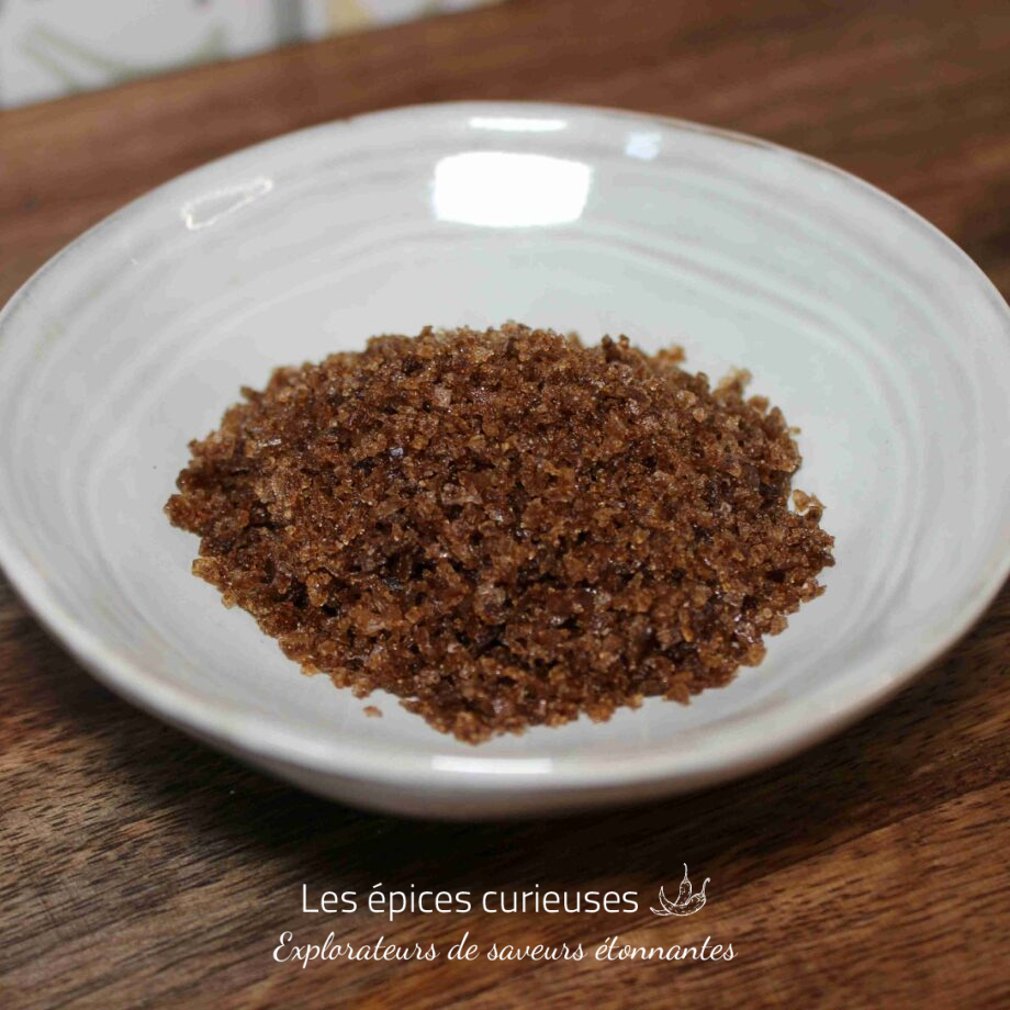 Sucre brun dans une assiette blanche sur une table en bois.
