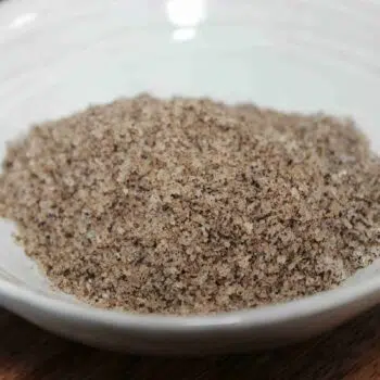 Sel aromatisé dans un bol blanc sur une table en bois, idéal pour rehausser les plats culinaires.