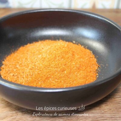 Assaisonnement orange vif dans un bol noir, idéal pour relever vos plats et recettes préférées.