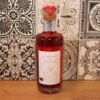 Bouteille de vinaigre artisanale rouge sur fond de carreaux décoratifs en céramique, étiquette dessinée à la main.