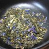 Mélange de thé vert avec fleurs séchées colorées dans un bol noir. Aromatique et visuellement attrayant.
