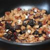 Mélange de fruits secs et baies dans un bol noir, prêt pour une infusion de tisane délicieuse et naturelle.