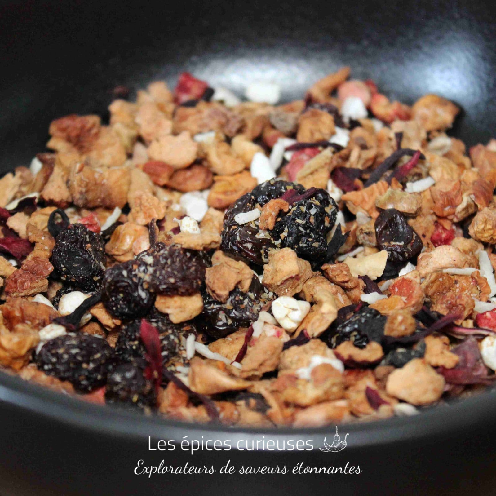 Mélange de fruits secs et baies dans un bol noir, prêt pour une infusion de tisane délicieuse et naturelle.