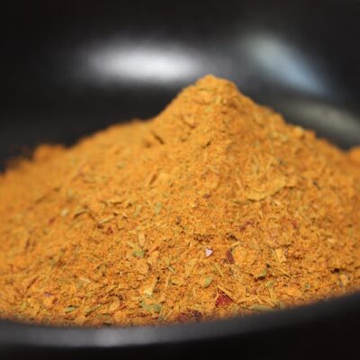 Monticule d'épices en poudre dorée dans un bol noir, prêt à enrichir vos plats de saveurs exotiques.