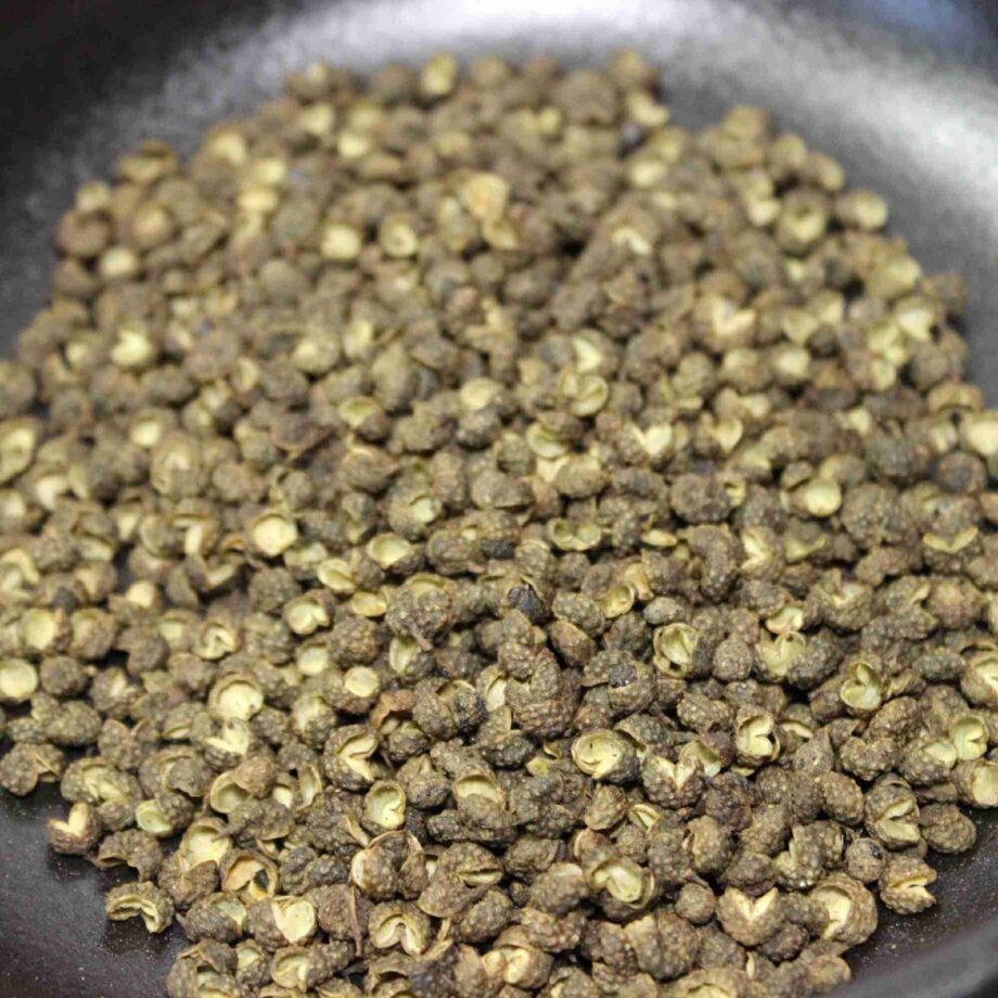 Grains de poivre vert dans une poêle, prêts à être utilisés pour rehausser vos recettes culinaires.