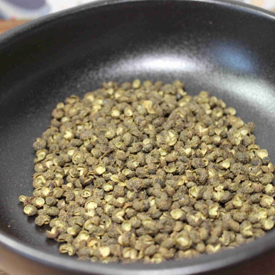Grains de poivre de Sichuan dans un bol noir pour une cuisine asiatique authentique et épicée.