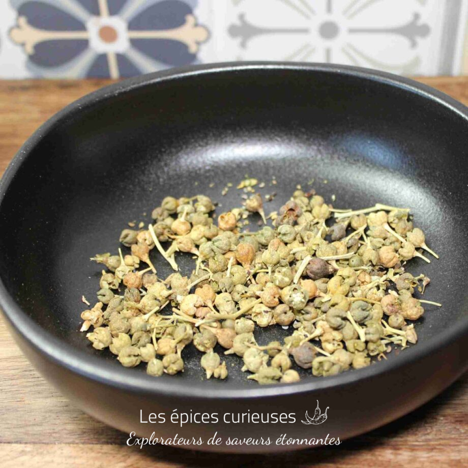 Graines séchées dans un bol noir sur une table en bois, avec des carreaux décoratifs en fond.