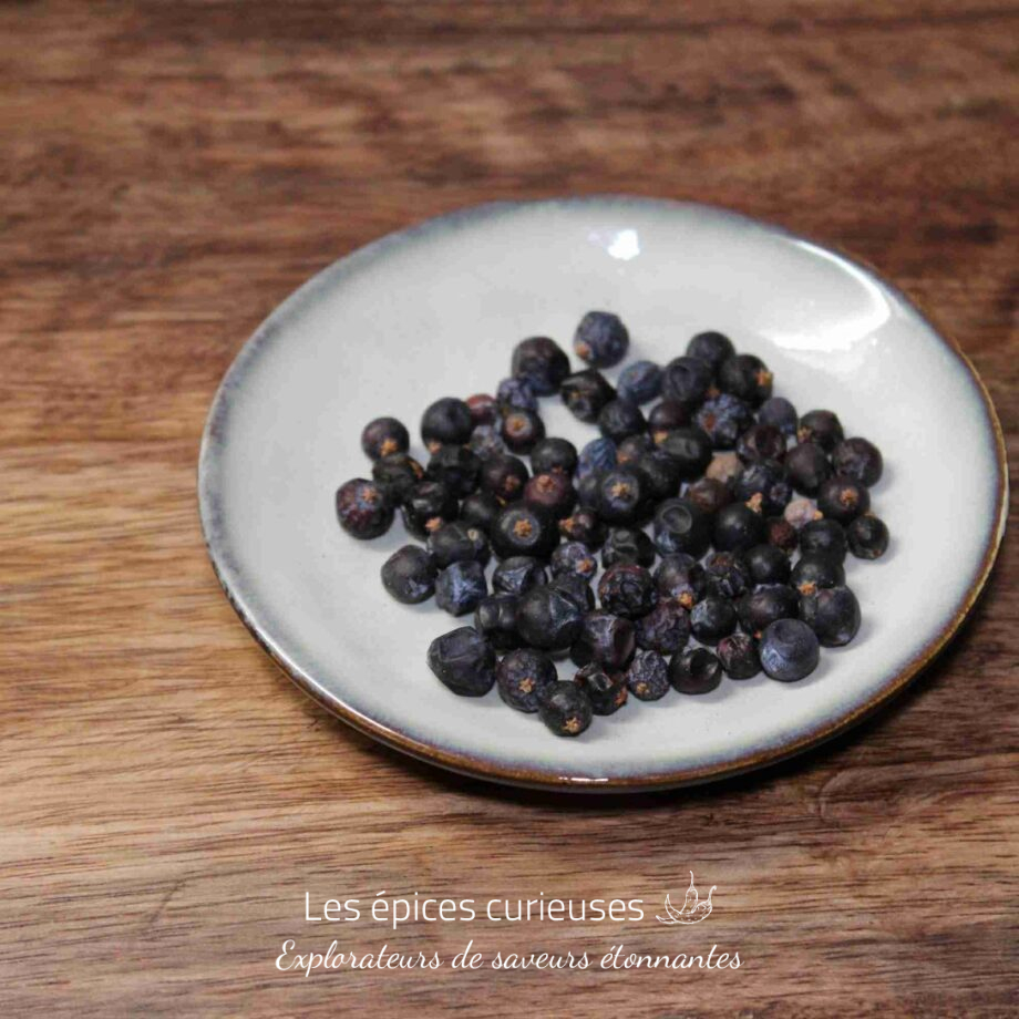Baies de genévrier séchées sur une assiette blanche en céramique, idéale pour aromatiser vos plats ou infusions.