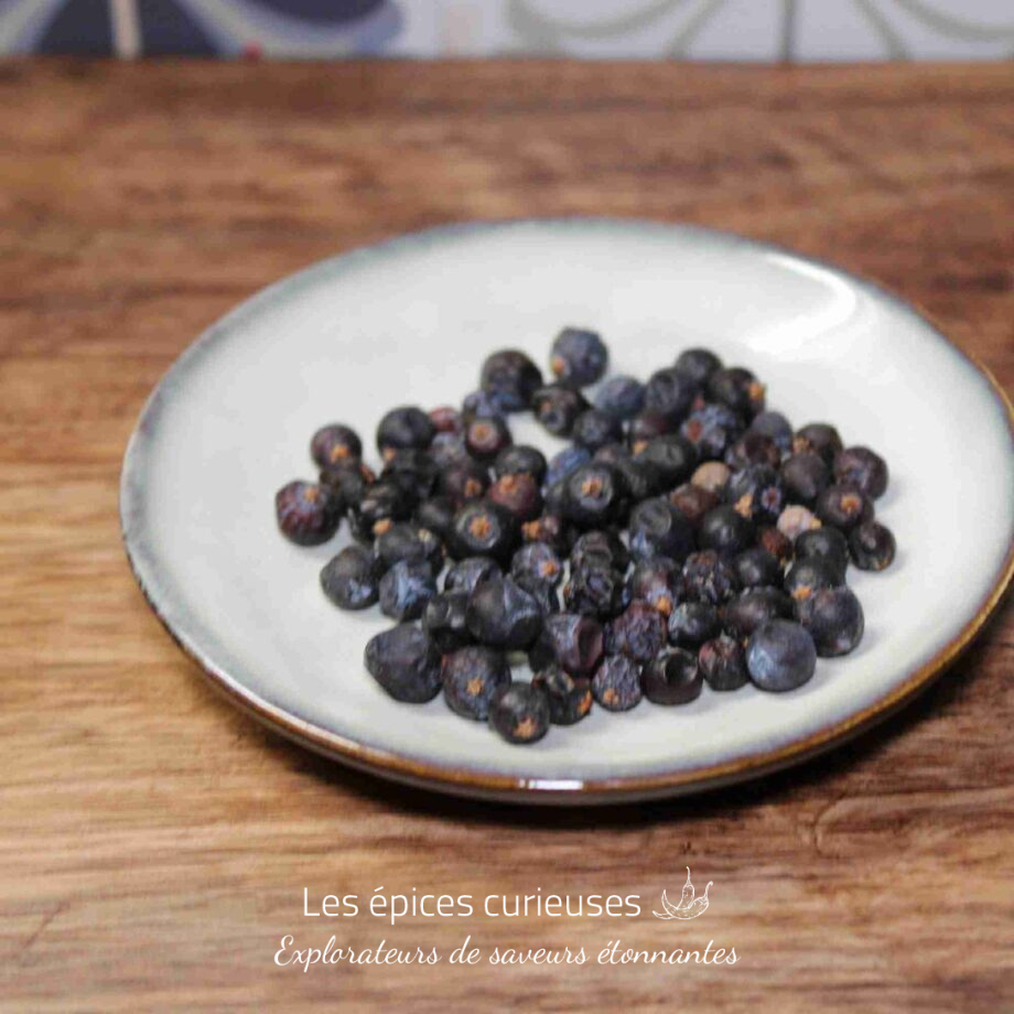 Assiette de baies de genièvre séchées sur une table en bois, épice aromatique pour cuisine et boissons.