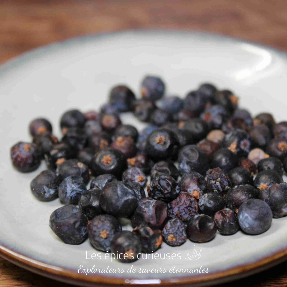 Baies de genièvre séchées sur une assiette blanche, idéales pour aromatiser les plats et boissons.