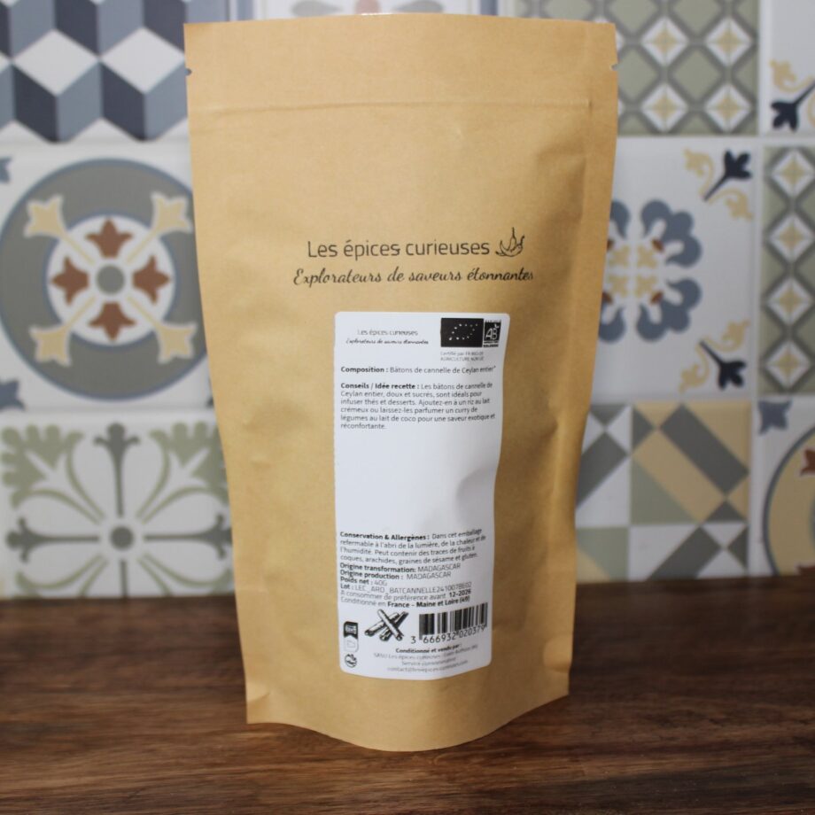 Paquet d'épices Les épices curieuses sur fond de carreaux colorés, mettant en avant des bâtons de cannelle de Ceylan.