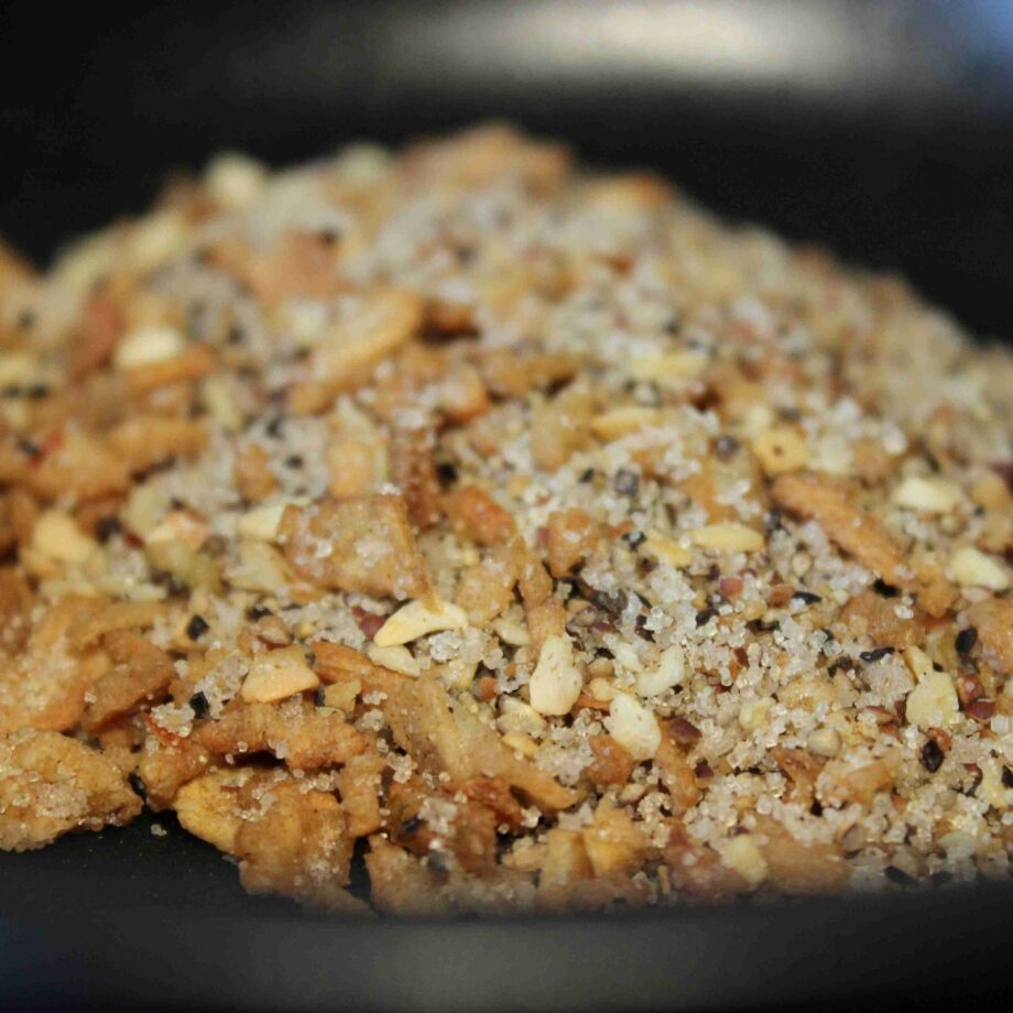 Mélange de noix concassées et épices sur fond noir, idéal pour ajouter du croquant et de la saveur aux plats.