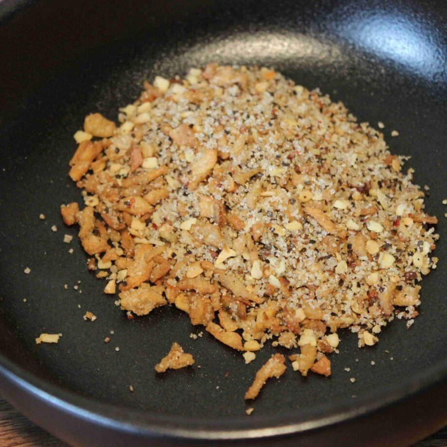 Assortiment de chapelure et d'épices dans une poêle noire pour un plat savoureux et croustillant.
