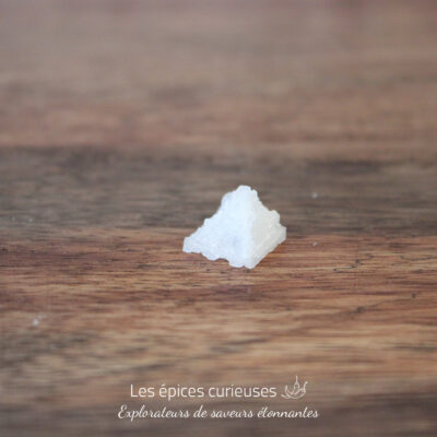 Cristal de sel en forme de pyramide sur une table en bois.