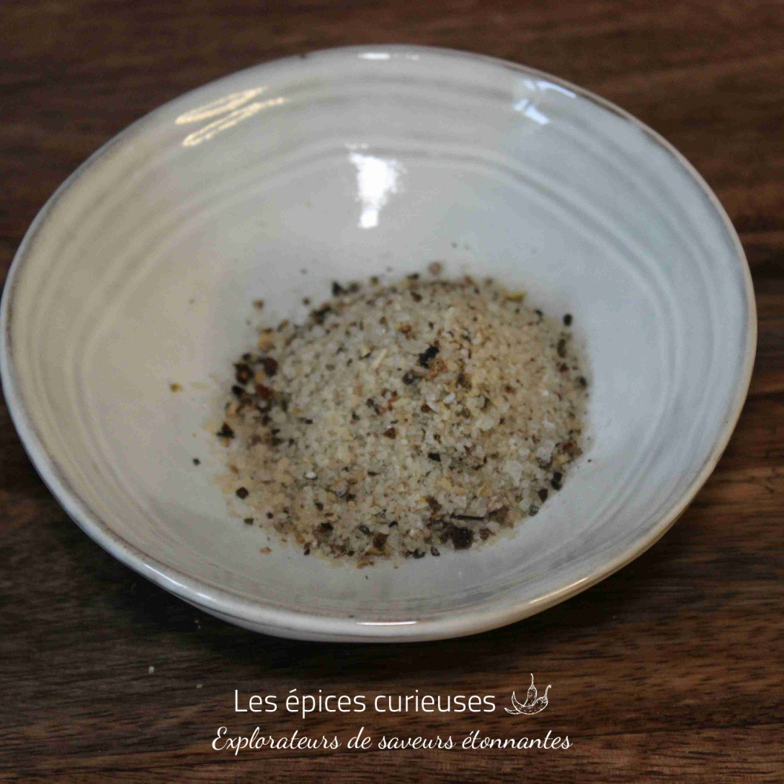 Assiette de sel de mer assaisonné, posée sur une table en bois. Parfait pour rehausser vos plats culinaires.