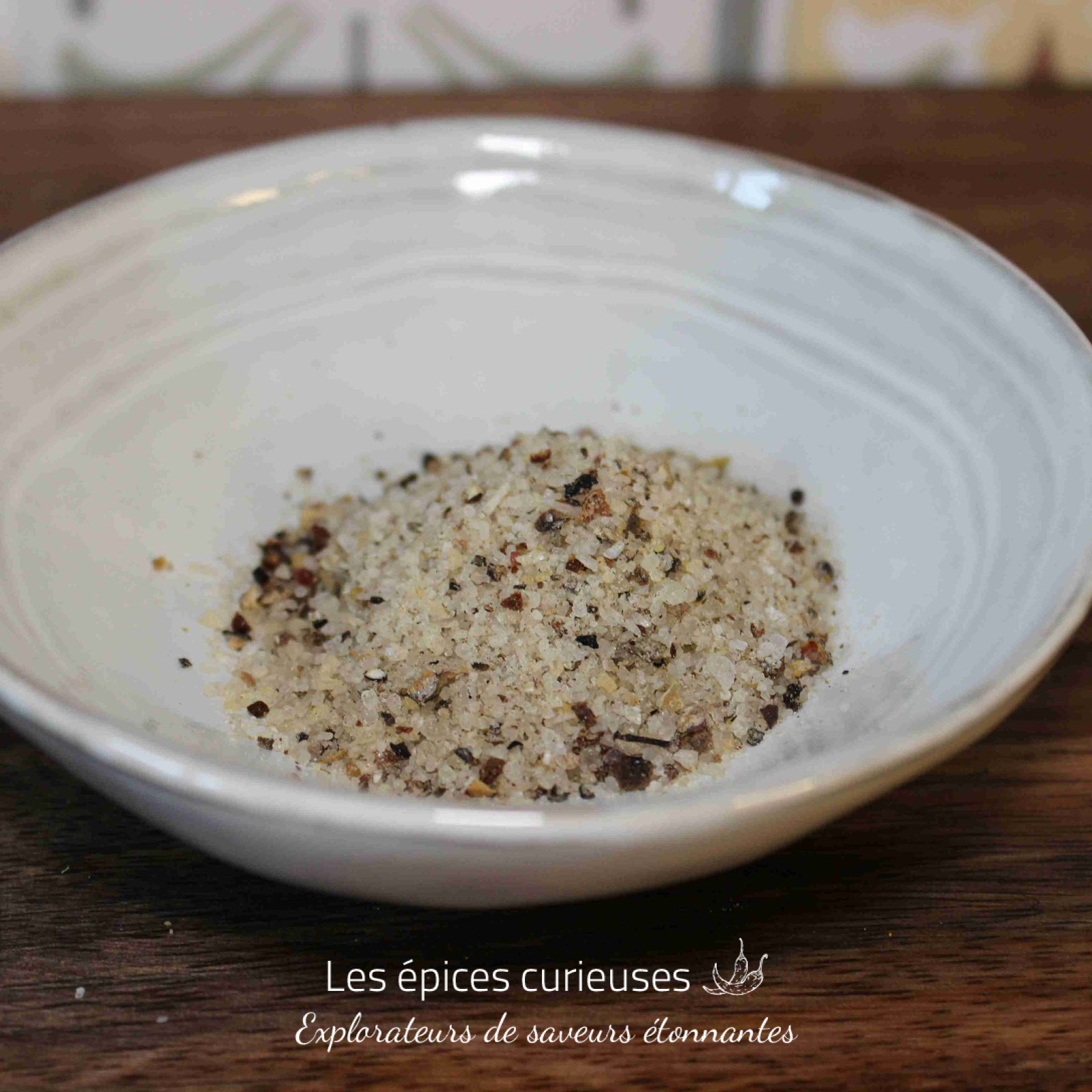 Bol en céramique contenant un mélange de sel et d'épices sur une table en bois.