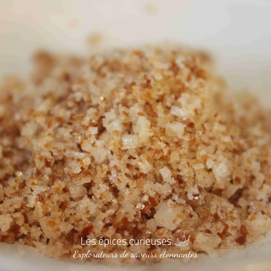 Gros plan de sucre roux en cristaux, illuminant sa texture et sa couleur unique.