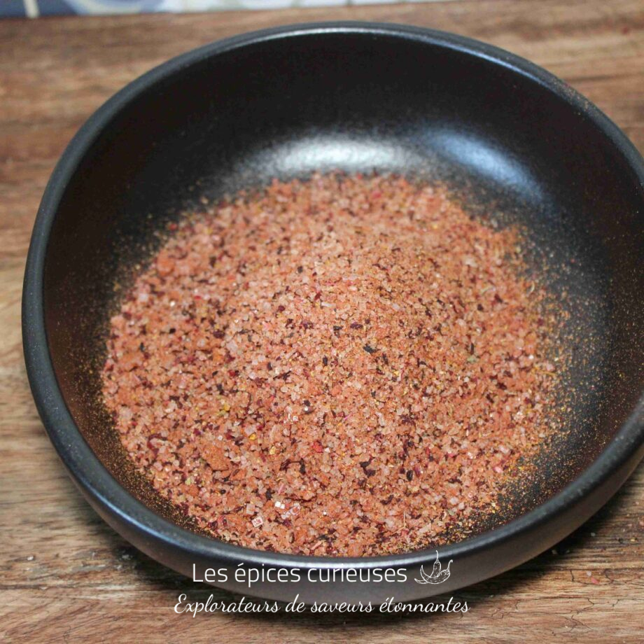 Bol de sel rose épicé sur une table en bois, prêt pour sublimer vos plats.