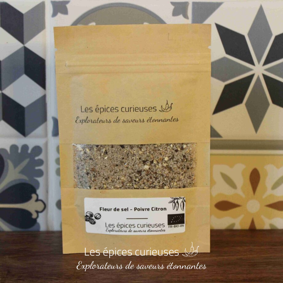 Sachet d'épices biologiques Les épices curieuses contenant fleur de sel et poivre citron, sur un fond de tuiles colorées.