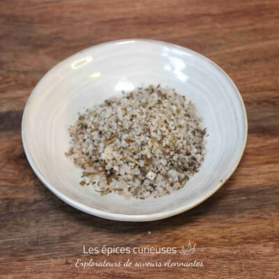 Bol de sel épicé mélangé avec herbes sur table en bois, prêt pour cuisiner.