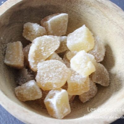 Morceaux de gingembre confit dans un bol en bois, délice sucré et épicé idéal pour agrémenter vos recettes exotiques.