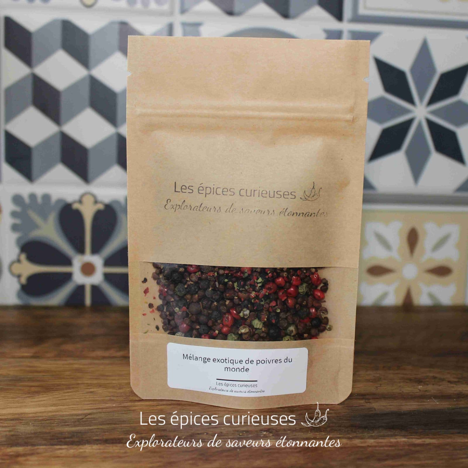Sachet de Mélange exotique de poivres du monde par Les Épices Curieuses, devant un mur de carreaux décoratifs.