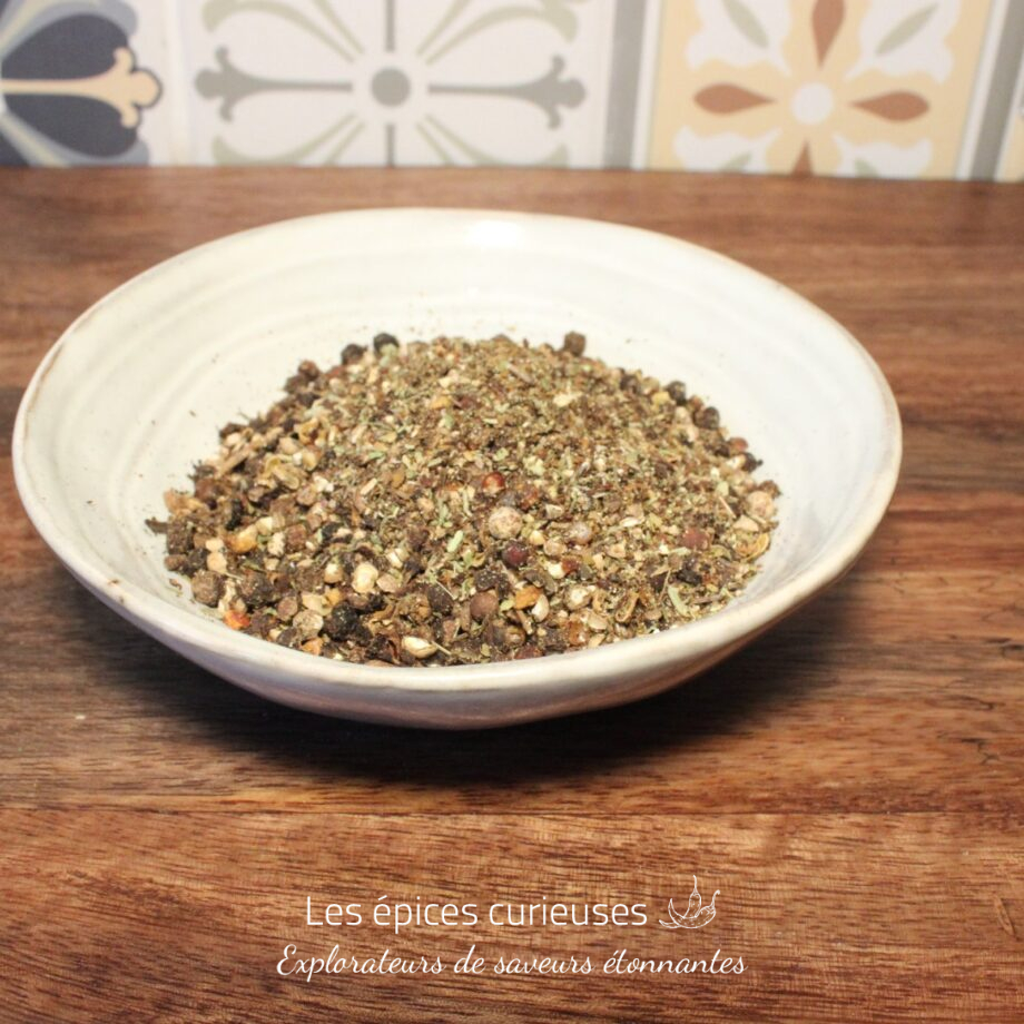 Bol de mélange d'épices sur table en bois, fond de carreaux colorés.