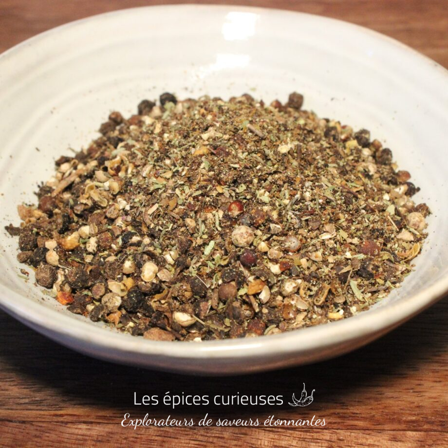 Assortiment de fines herbes et épices séchées dans un bol blanc sur une table en bois.
